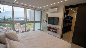 Ein Schlafzimmer mit großem Fenster, einem Bett, einem Fernseher und einem Kleiderschrank.