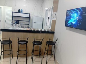 A kitchen with a marble countertop, a refrigerator, and a TV mounted on the wall. - Pousada Do Goiano. Blue Rivers + over 20 rivers just a few minutes away. Make a reservation now. (Aurora do Tocantins)