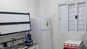 Una cocina con refrigerador, horno y ventana con persianas.