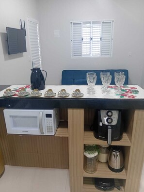 A kitchen with a microwave, coffee maker, and a table set with teapots and glasses. - Pousada Do Goiano. Blue Rivers + over 20 rivers just a few minutes away. Make a reservation now. (Aurora do Tocantins)