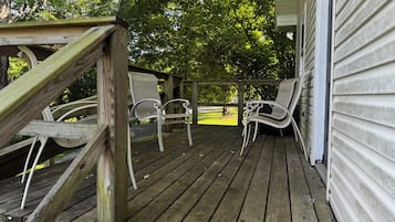 Une terrasse en bois avec deux chaises blanches et une rambarde en bois.