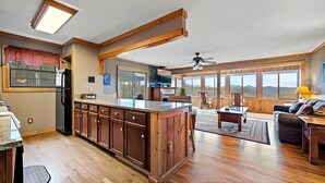 A spacious kitchen with wooden cabinets, a large island, and a dining area with a sofa and table. - Mountain Getaway with Big Views, 3 King Beds, Game Room, Hot Tub, Pet Friendly! (Sevierville)