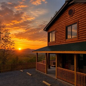 A wooden cabin with a covered porch and a view of the sunset. - Fall Mountain Getaway: Big Views, 3 King Beds, Game Room, Hot Tub, Pet Friendly! (Sevierville)