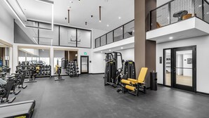 A gym with various exercise equipment, a mezzanine level, and a modern interior design. - Luxury 1BR Downtown Miami I Free Parking + Pool (Miami)