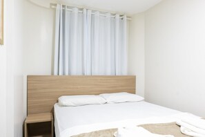 A single bed with a wooden headboard, a white pillow, and a white bedspread. - Porto Residence (Ipojuca)