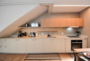 Una cocina moderna con horno empotrado, cafetera y lavaplatos.