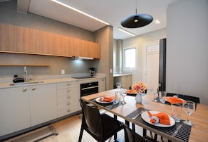Una cocina moderna con comedor, que incluye un amplio ventanal, armarios empotrados y una mesa de comedor preparada para cuatro personas.