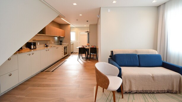 Un apartamento moderno con cocina, comedor y sala de estar con sofá y sillón.
