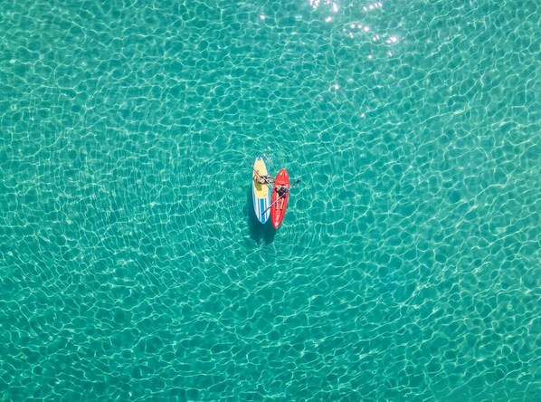 A red kayak on clear turquoise water.