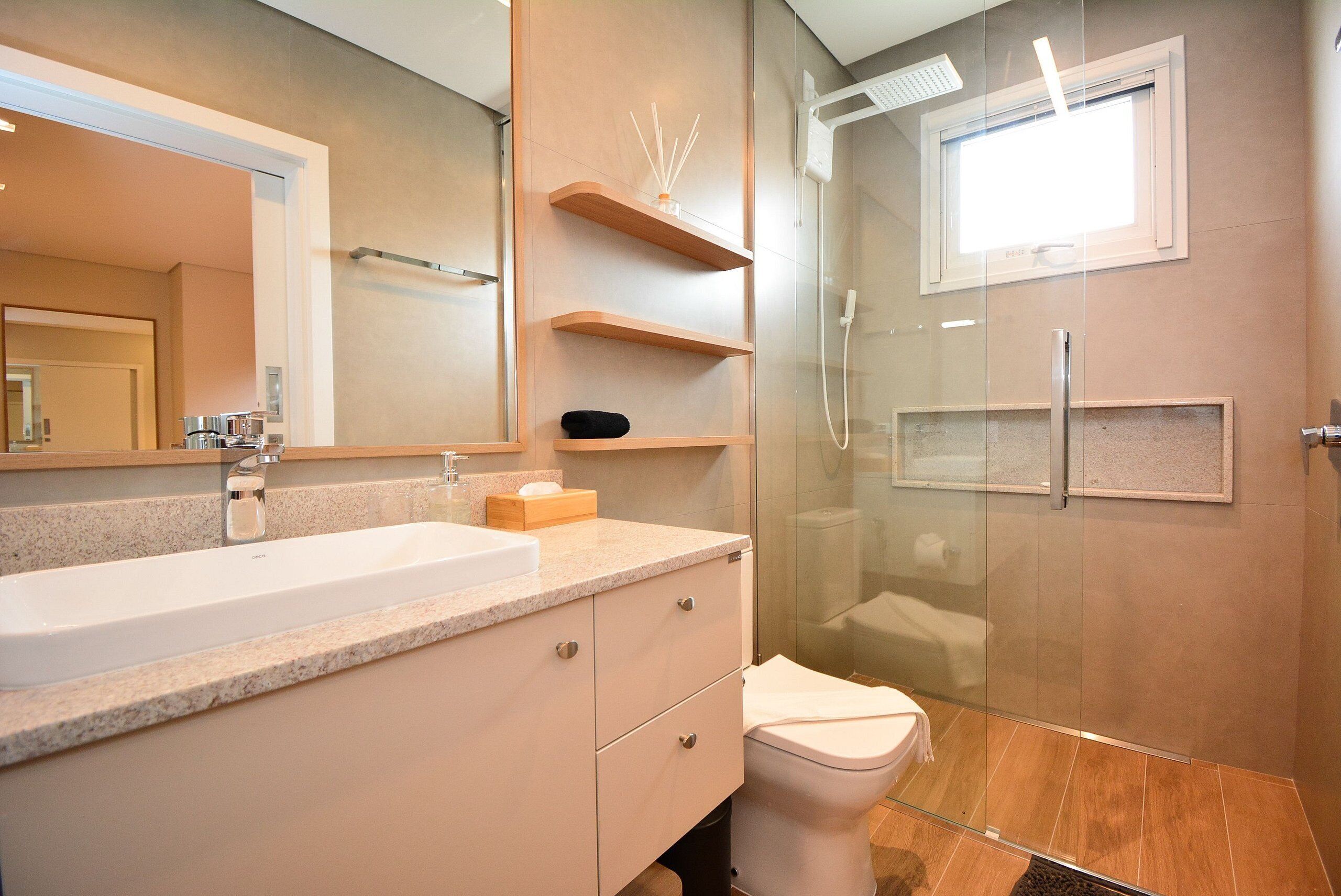 A modern bathroom with a large sink, mirror, and glass shower enclosure.