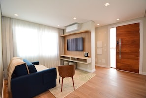 Una sala de estar moderna con sofá, televisor y suelo de madera.