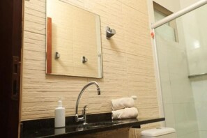 A bathroom with a black countertop, a mirror, a towel rack, and a glass shower enclosure. - Pousada Casa Boa Milagres (Passo de Camaragibe)