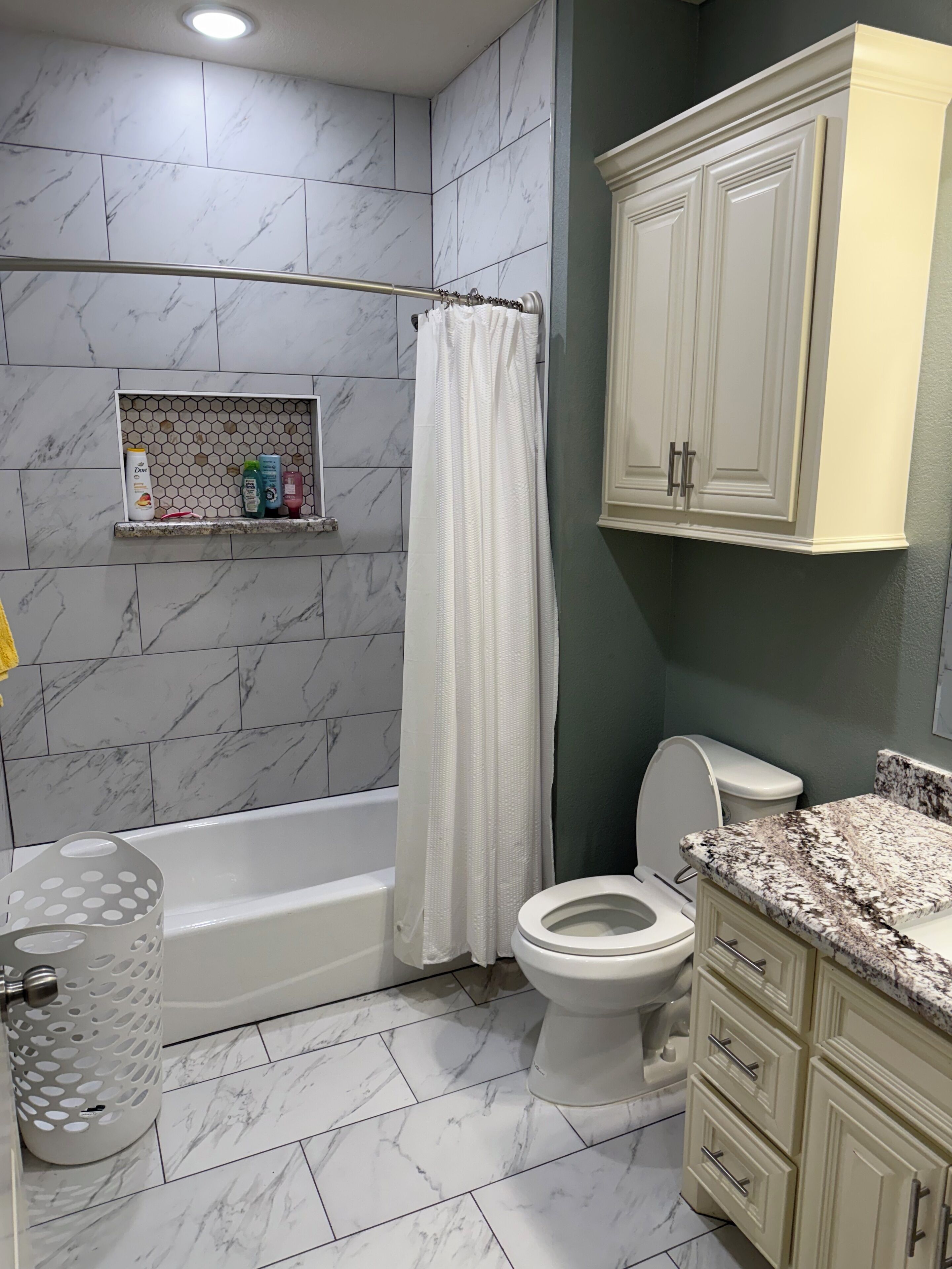 A bathroom with a bathtub, toilet, and vanity with drawers.