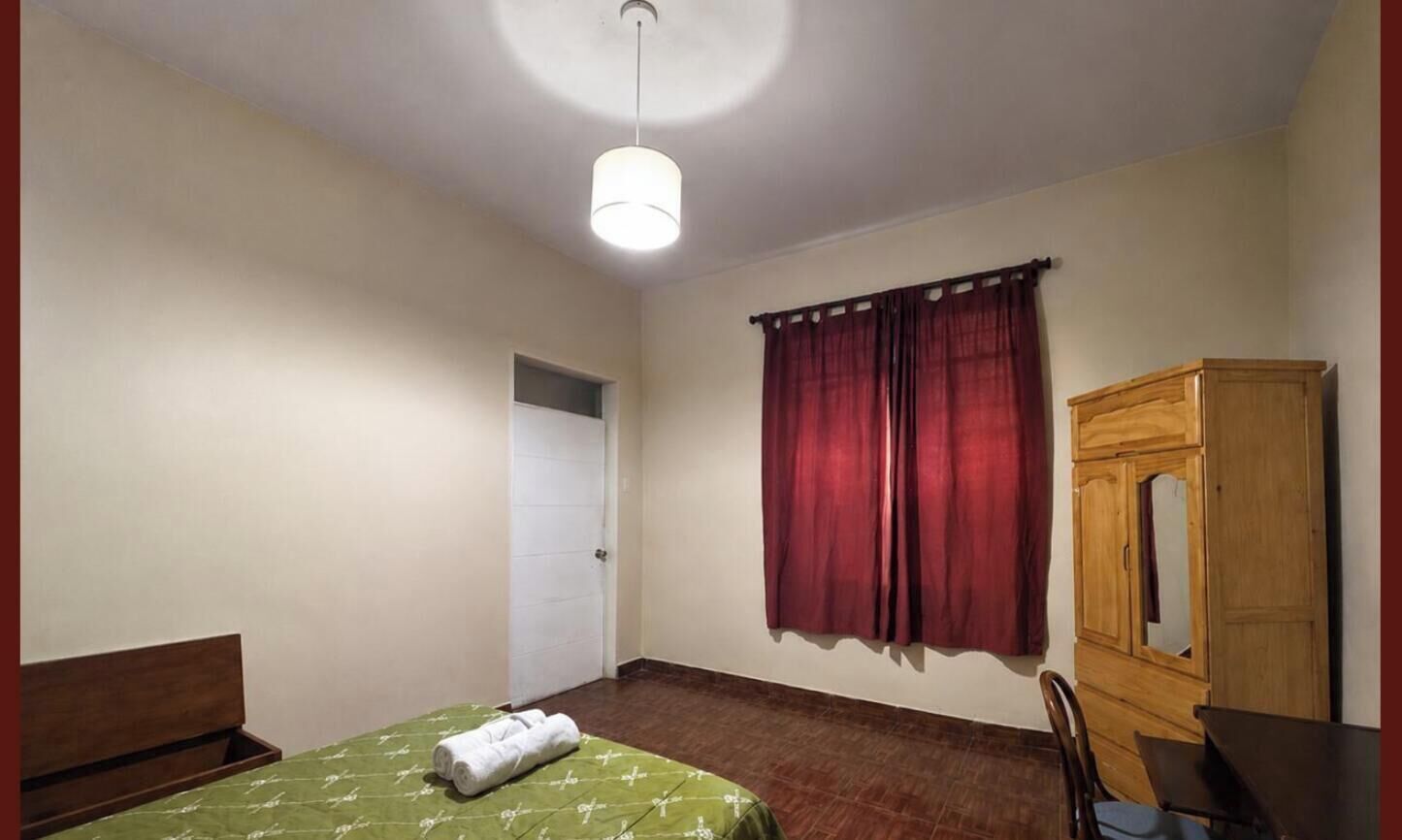 Une pièce comprenant un lit, une armoire en bois, une chaise et une porte.