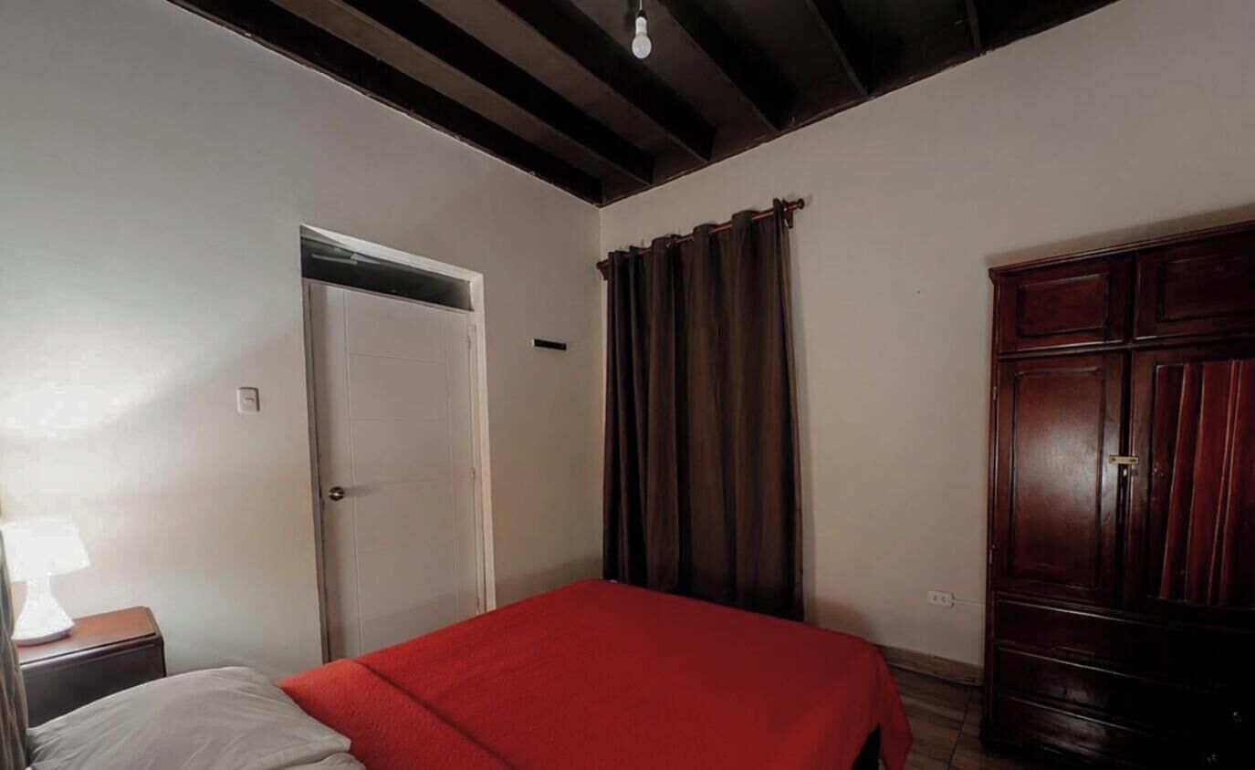 Una habitación con cama, armario, puerta y cortina.