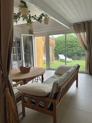 Ein Zimmer mit einer Holzbänkl, einem Tisch und einem Korb. Eine Tür führt nach draußen.