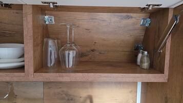 A wooden cabinet with a wine glass, a glass, and a metal container.
