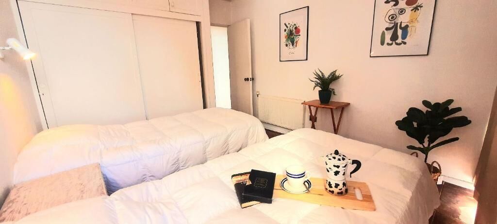 Een kamer met twee bedden, een nachtkastje met een plant en een radiator.