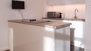 A modern kitchen with a built-in island, a flat-screen TV, and a microwave. - The Tenter Ground  Liverpool Street (London)