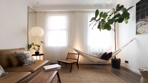 A living room with a sofa, a chair, a small table, a hammock, and a large plant. - The Tenter Ground  Liverpool Street (London)