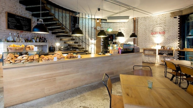 Ein Café mit Backsteinwand, Holztresen und hängenden Pendelleuchten.