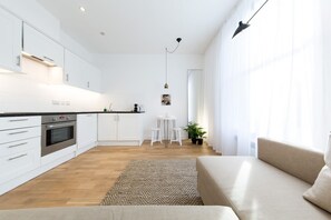 A modern kitchen with white cabinets, a dining area with a white table and chairs, and a living area with a beige sofa. - The Holborn Hideaway by The Design Traveller (London)
