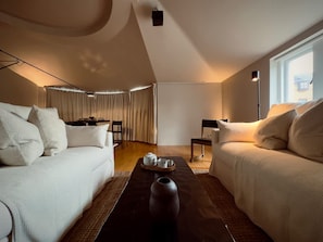 Ein modernes, helles Wohnzimmer mit einer Couch, einem Couchtisch und einem Essbereich.