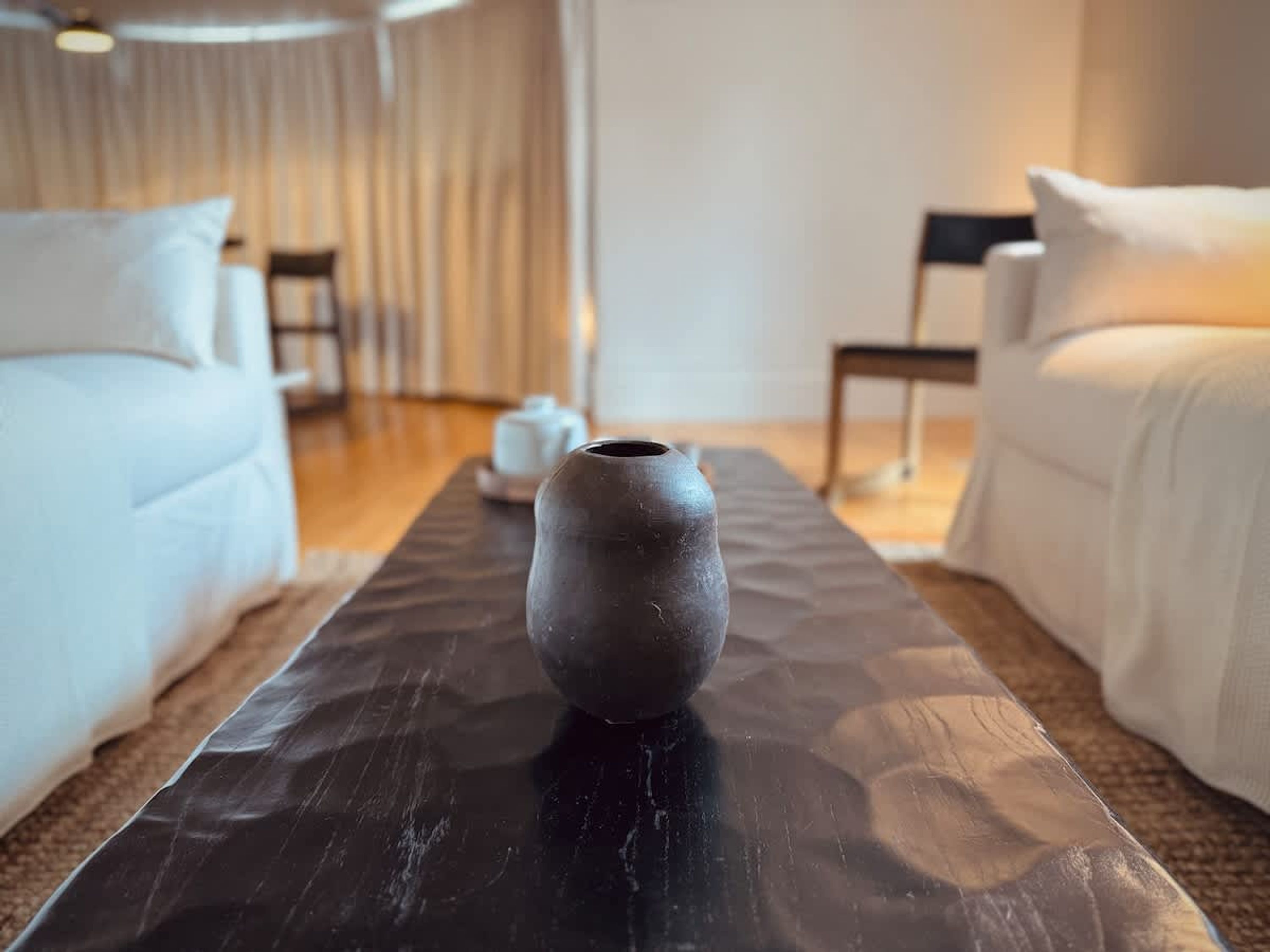 A modern room with a black table, a white sofa, and a chair.
