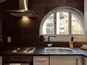 Eine moderne Küche mit Gaskochfeld, Edelstahlspüle und einem Fenster mit Bogenform.