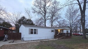 A single-story mobile home with a porch and a staircase leading to a deck.