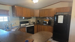 A kitchen with wooden cabinets, a stove, a microwave, and a refrigerator.