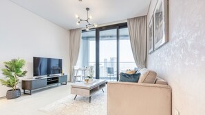 Una sala de estar moderna con un televisor de pantalla plana, un sofá, una mesa de centro, una planta en maceta y un balcón con vista a la ciudad.