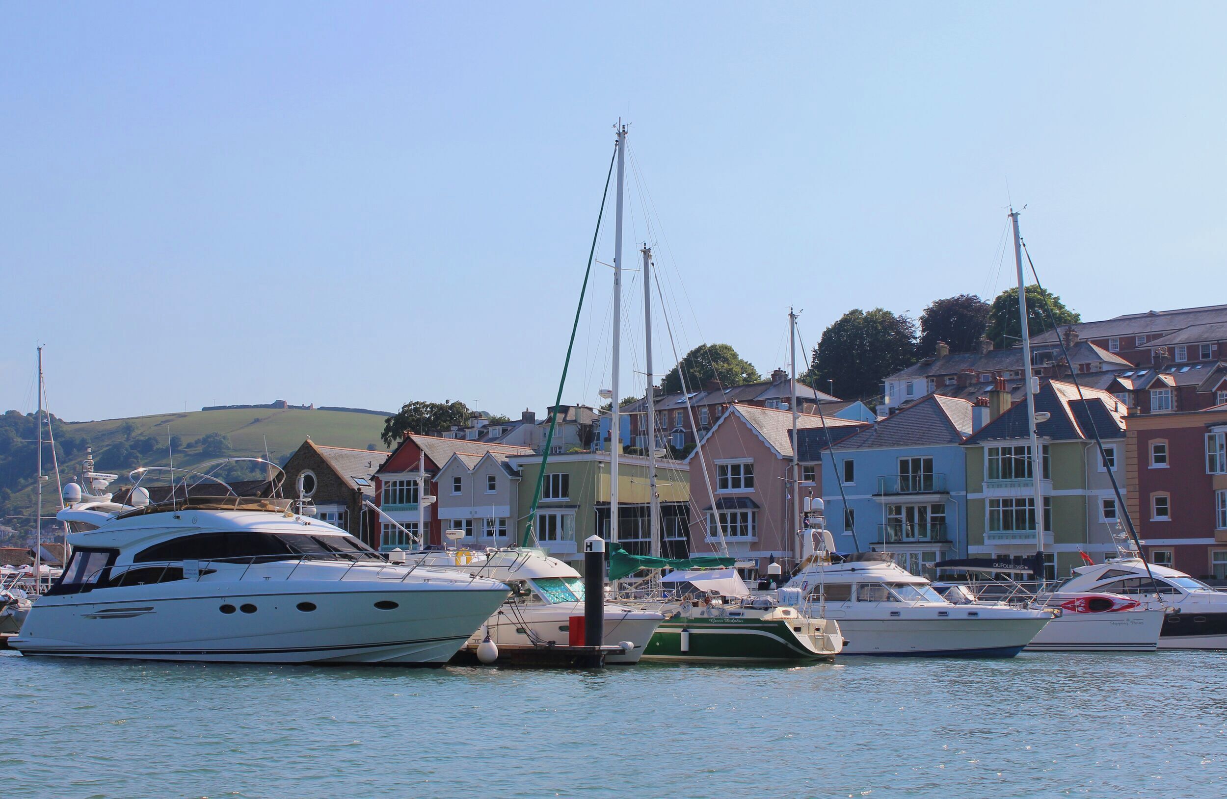 A marina with several yachts docked, surrounded by colorful houses.