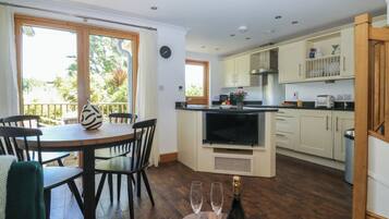 Una cocina con comedor, televisor y una botella de champán.