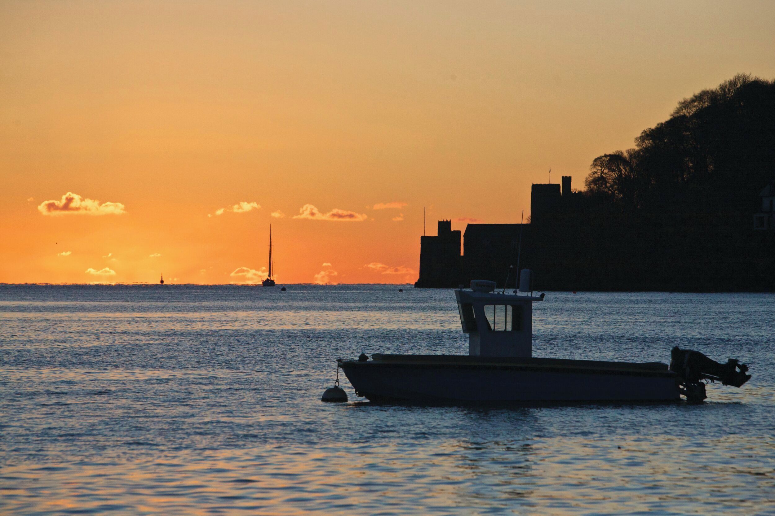 Un barco atracado en un puerto con el sol poniéndose al fondo.