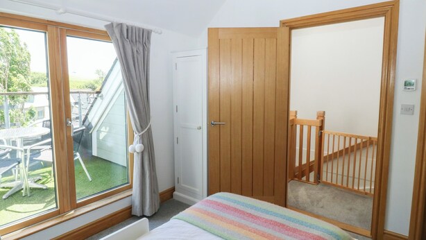 Een slaapkamer met een bed, een raam met gordijnen, een deur en uitzicht op een buitenruimte met een tafel en stoelen.