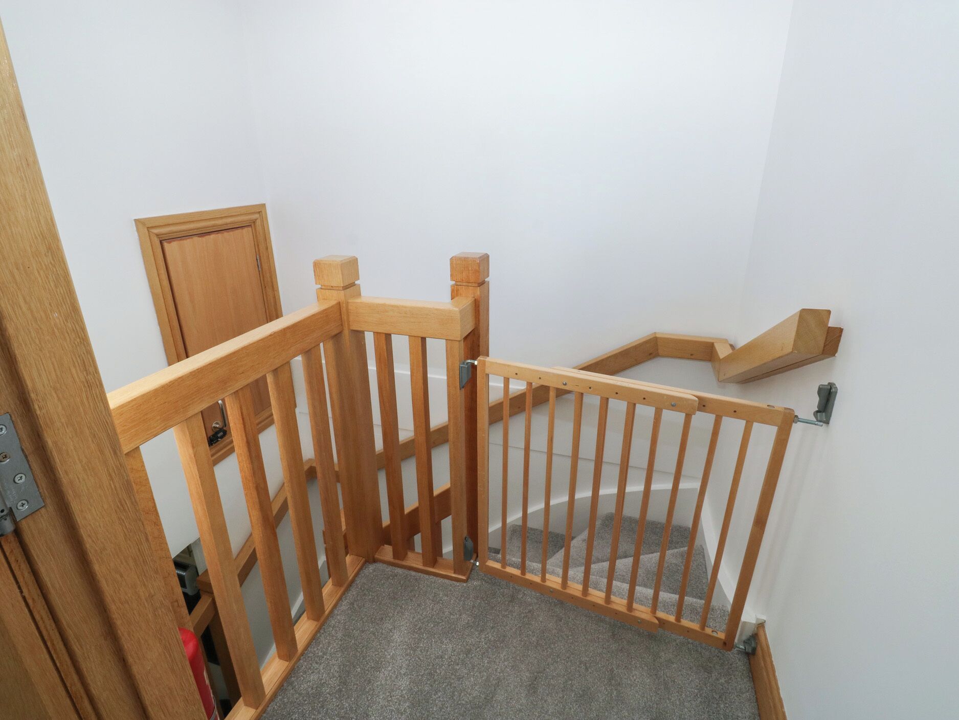 Una escalera de madera con barandilla y un rellano alfombrado.