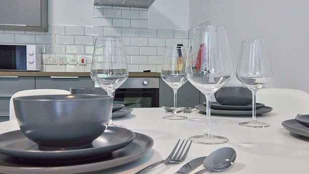 Une table à manger dressée avec des assiettes, des bols, des couverts et des verres à vin.