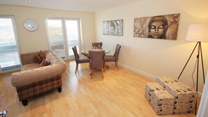 A living room with a sofa, a dining table with chairs, a clock, and artwork on the walls. - The View in Newcastle Upon Tyne (Newcastle Upon Tyne)