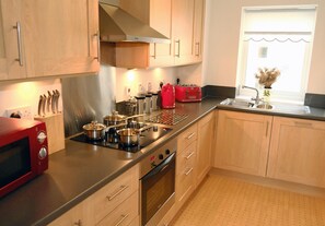 A modern kitchen with wooden cabinets, stainless steel appliances, and a window with a view. - Regent in Gosforth with 2 bedrooms and 2 bathrooms (Gosforth)