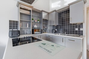 Eine moderne Küche mit integrierten Geräten, einer Arbeitsplatte mit Küchenläufer und grauen Schränken.