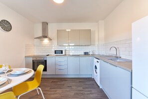 A compact kitchen with white cabinets, a microwave, a sink, and a built-in oven. - Mindrum in North Shields (North Shields)
