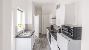 Una cocina moderna con armarios blancos, encimera negra y horno integrado.