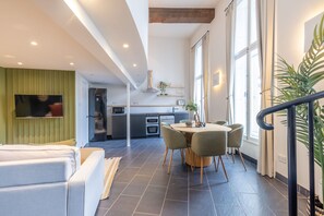 A modern living room with a sofa, a dining area with a table and chairs, a kitchen in the background, and large windows providing natural light. - Watergate in Newcastle Upon Tyne (Newcastle Upon Tyne)