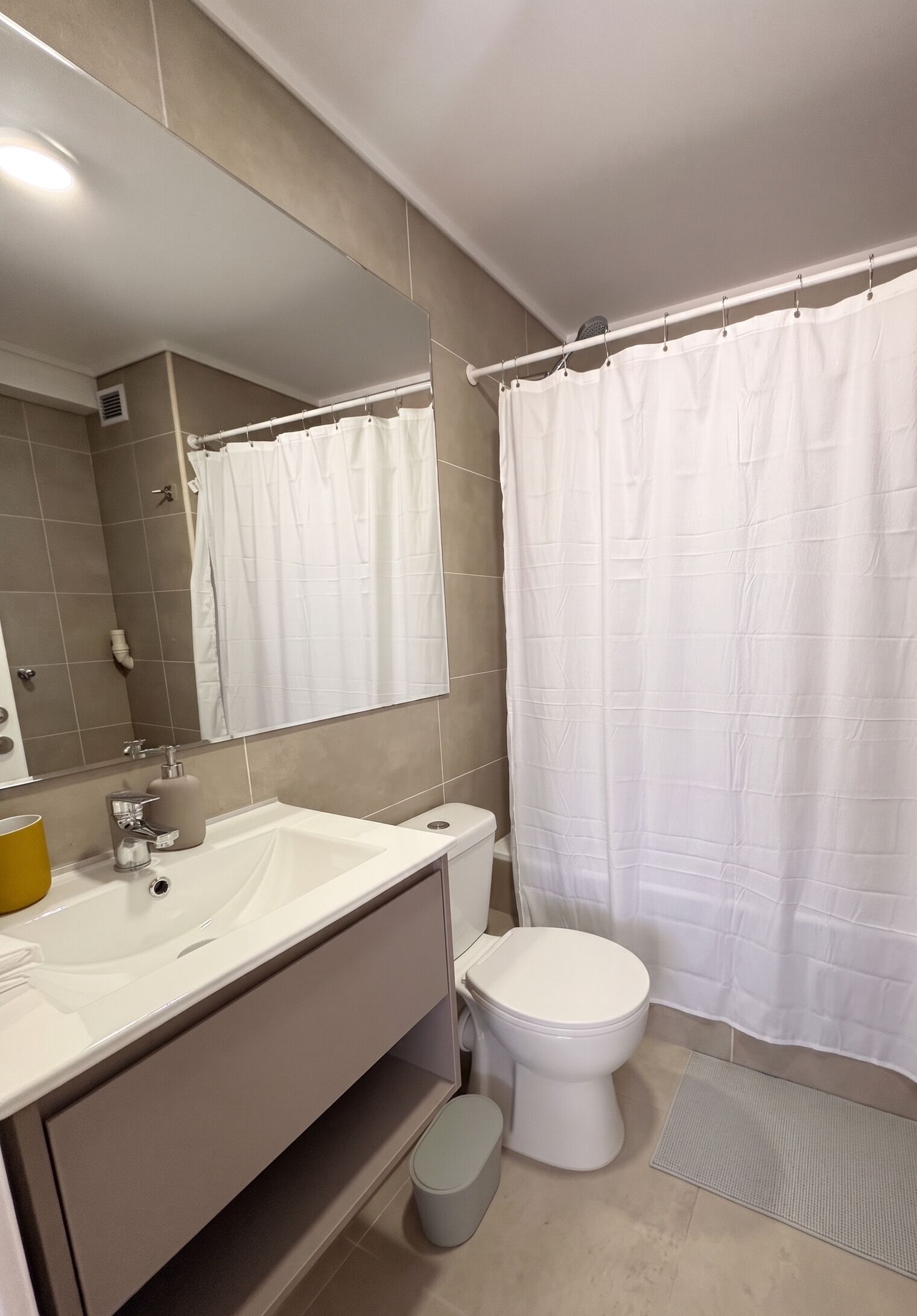 A bathroom with a white sink, toilet, and shower curtain.