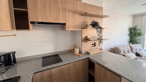 Una cocina moderna con armarios de madera, una placa de inducción negra y una campana extractora integrada.