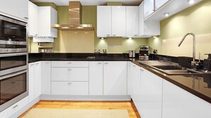 Una cucina moderna con mobili bianchi, elettrodomestici in acciaio inossidabile e un piano di lavoro nero.