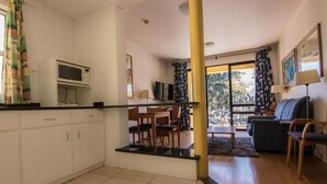 Una cocina moderna con armarios blancos, un microondas y un comedor con mesa y sillas.