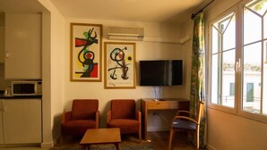Una sala de estar con dos sillones, una mesa de centro, un televisor y obras de arte en la pared.