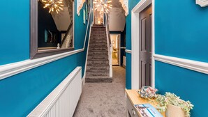 A hallway with teal walls, a carpeted staircase, and a door leading to another room. - Sandhaven House in South Shields (South Shields)